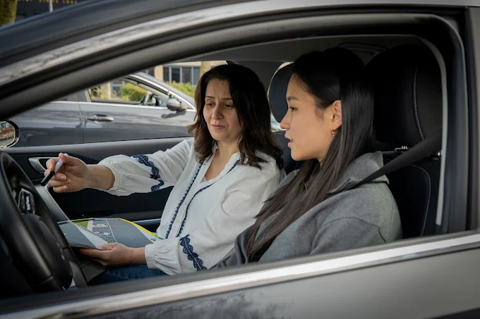 Geslaagde leerling steekt haar duim op naast de lesauto van Rijschool Simplicity